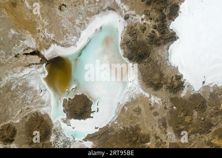 May 7, 2023 - Bolivia - An astronaut aboard the International Space Station captured this photograph of Salar de Coipasa and neighboring Salar de Uyuni in the Bolivian Andes. Visible from low Earth orbit, the salt flats display stark white hues that contrast with the darker surrounding rock. Various volcanic cones are scattered through the image, such as Cerro Tetivilla, which divides the two salt lakes; Wila Pukarani, located within the Coipasa Salt Flat; and Paryani, on the northern edge of Coipasa. In recent years, Andean salt flats have been the subject of climate and space-based analog st Stock Photo