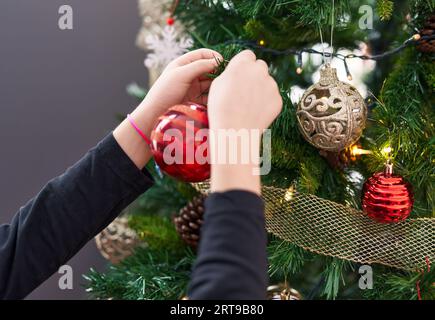 Adorable hispanic girl decorating christmas tree at home Stock Photo