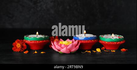 Glowing candles and flowers for Indian holiday Diwali (Festival of lights) on dark background Stock Photo