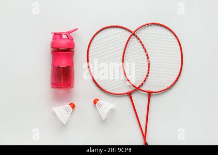 Badminton  rackets, shuttlecocks and bottle of water on light background Stock Photo
