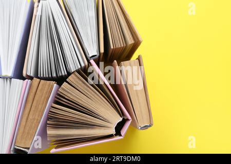 Many half open books on yellow background Stock Photo