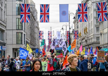 LONDON - April 24, 2023: The Strand in London becomes a sea of colourful XR protest flags beneath suspended Union Jacks, a powerful climate activism d Stock Photo