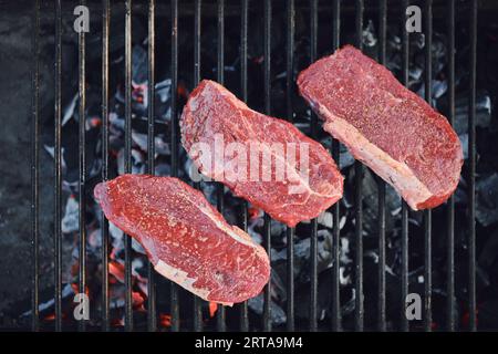 Top view of beef strip steaks on grid of grill Stock Photo