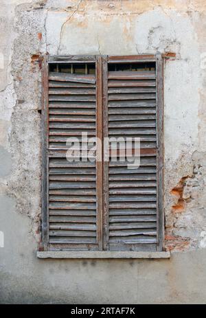 old window with shutters, an ancient wall facade with slightly broken wooden window perfect as background textures Stock Photo