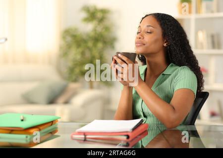 Black student relaxing drinking coffee sitting and breathing at home Stock Photo