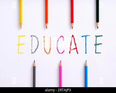 The handwritten word educate and colorful crayons on white background. Preschool education concept. Stock Photo