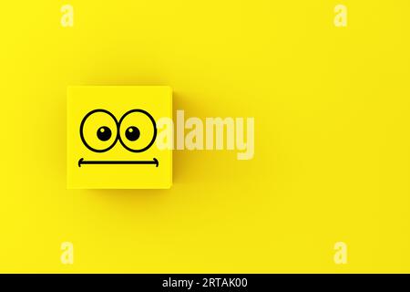 Neutral or surprised emoticon face on a yellow cube block. Stock Photo