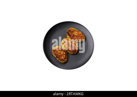 Diet vegetable cutlet from zucchini, carrot, herbs on a black plate on a dark concrete table. Healthy food Stock Photo