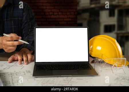 architect engineers Working on a desktop computer on a laptop mockup screen with an architectural project and blueprint on a desk working equipment in Stock Photo