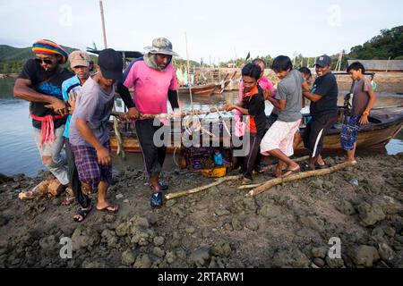 Koh Yao, Thailand; 1st January, 2023: A group of Thai fishermen loading the engine of a boat. Stock Photo