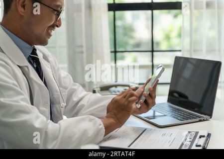 Doctor Smiling working with mobile phones and remote online services at the clinic smart medical doctor high quality service concept Stock Photo