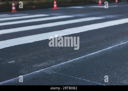 Process of making new road surface markings with a line striping machine, workers improve city infrastructure, demarcation marking of pedestrian cross Stock Photo