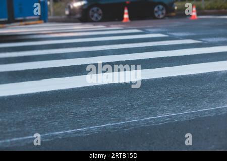 Process of making new road surface markings with a line striping machine, workers improve city infrastructure, demarcation marking of pedestrian cross Stock Photo