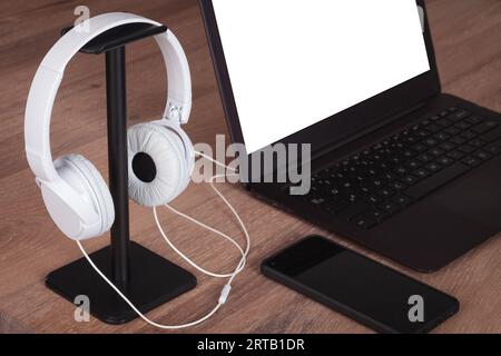 Modern Office Desk with Laptop and White Headphones, blank screen. Stock Photo