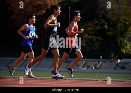 Japanese athletes running on track Stock Photo