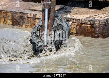 Dredging the bottom of water area, view of the bucket of the floating excavator full of mud Stock Photo