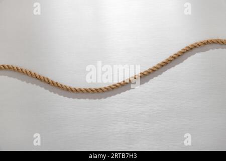 Top view of curved natural jute rope placed on gray table in sunlight Stock Photo