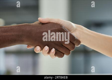 Close-up of hands of young intercultural patient and clinician giving each other handshake in front of camera after signing medical document Stock Photo