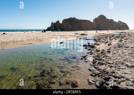 Pfeiffer Beach in Big Sur, California. View of rock through which the tunnel passes, fine sand, crystal blue Pacific water and clear sky above Montrey Stock Photo