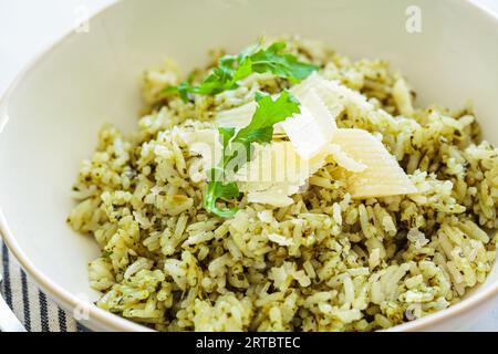 Green pesto risotto with parmisan, white marble background, close-up. Stock Photo