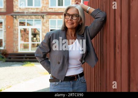 gray-haired mature dreamy woman dressed for summer walks around the city Stock Photo