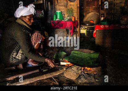 DORZE, ETHIOPIA - JANUARY 30, 2020: Dorze woman is preparing kocho bread made of enset in a traditional hut woven out of bamboo, Ethiopia Stock Photo