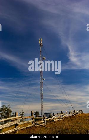 Telecommunication tower with radio, microwave and television antenna system located in the forest against the blue sky. Antenna tower, view from the g Stock Photo