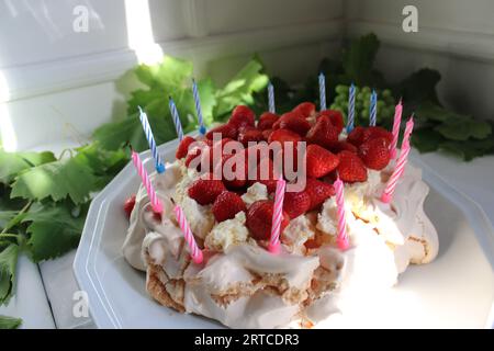 Strawberry pavlova meringue dessert birthday cake with pink and blue candles Stock Photo