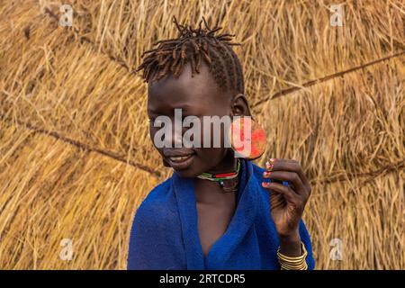 OMO VALLEY, ETHIOPIA - FEBRUARY 6, 2020: Mursi tribal girl in her village, Ethiopia Stock Photo