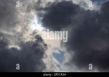zenith pointed incoming storm cloudscape with heavy clouds and sun between them, full-frame real life photo Stock Photo