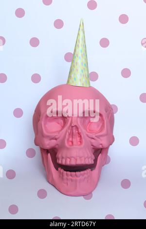 pastel pink skull with a colorful party hat and a dotty background Stock Photo