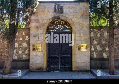 Main entrance to the Patriarchate of the Georgian Orthodox Church, Tbilisi, Georgia. The double-leaf wrought-iron gate, featuring depictions of saints, is set within a round arch made of sandstone blocks; two gilded plaques in Georgian and English mark the seat of the Catholicos-Patriarch of All Georgia. Shavteli Street, Kala, Ortachala, Krtsanisi District, Tbilisi, 0108, Georgia Stock Photo