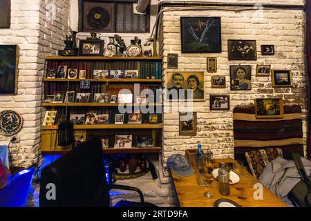 The interior of the Nikolozi restaurant in Tbilisi’s Old Town: whitewashed brick walls, shelves lined with books and personal belongings, and dozens of framed family photographs and portrait paintings all contribute to the restaurant’s nostalgic atmosphere. The restaurant, run by owners Dodo (a former professional footballer) and Beso, serves Georgian home-style cooking accompanied by their own wine – cash payments only. Anton Katalikos Street, Kala, Ortachala, Krtsanisi District, Tbilisi, 0108, Georgia Stock Photo