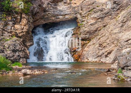 Running Eagle Falls in the Two Medicine section of Glacier National Park in Montana. Water flows both from the rock and over the top at times. Stock Photo
