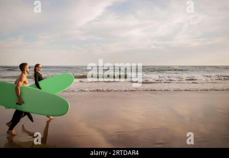 Sporty young couple having fun while surfing together at sunset Stock Photo
