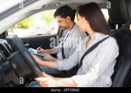 Handsome young man instructor examining woman driver Stock Photo
