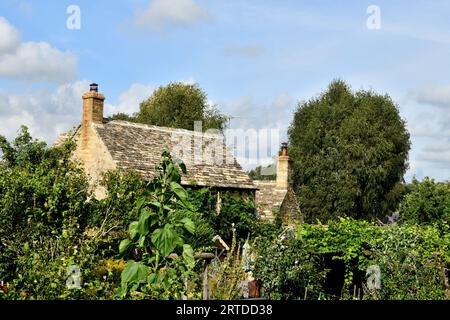 A beautiful stone cottage surrounded by a beautiful garden in the Cotswolds Village of Guiting Power on a bright sunny September day with blue sky Stock Photo