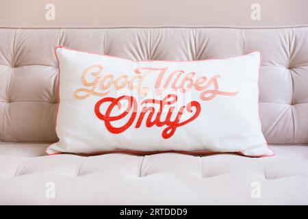 Close up of a good vibes only cushion on a pale pink sofa with space for text Stock Photo