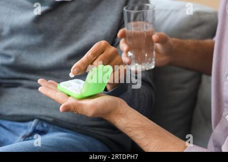 Senior man with his son taking pills at home, closeup Stock Photo