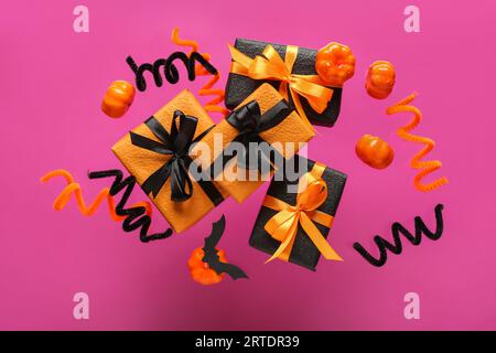 Flying gift boxes and Halloween decoration on pink background Stock Photo