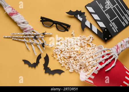 Composition with tasty popcorn, clapperboard, skeleton hands, 3D glasses and paper bats for Halloween celebration on beige background Stock Photo