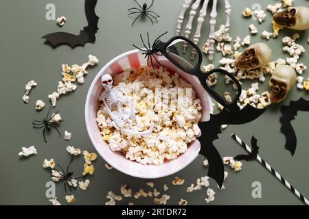 Bucket with tasty popcorn, 3D glasses and Halloween decor on green background Stock Photo