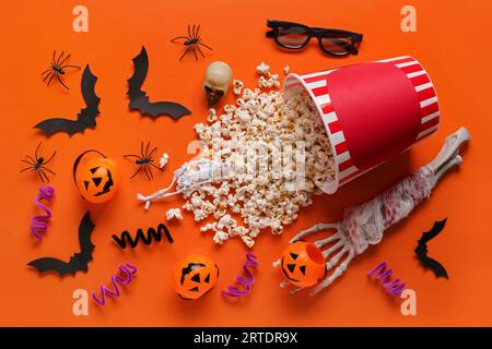 Composition with tasty popcorn, pumpkins, skeleton hand, paper bats and 3D glasses for Halloween celebration on orange background Stock Photo