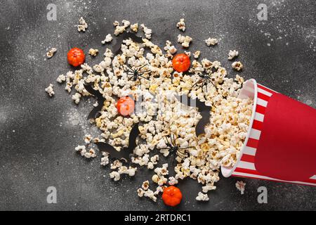 Overturned bucket with popcorn and Halloween decor on grey grunge background Stock Photo