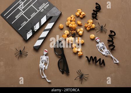 Movie clapperboard, caramel popcorn and Halloween decor on brown grunge background Stock Photo