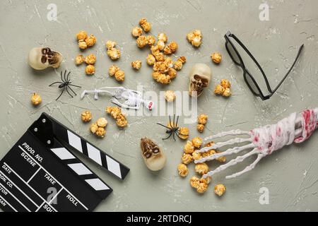 Caramel popcorn, movie clapperboard and Halloween decor on grey grunge background Stock Photo