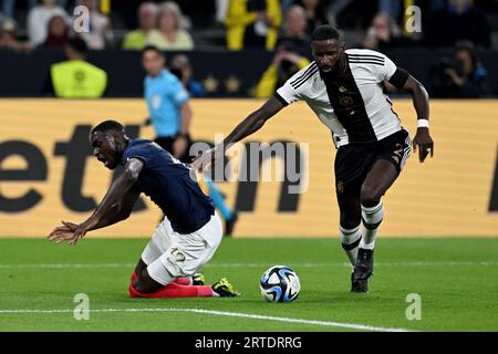Dortmund, Germany. 12th Sep, 2023. Soccer: Internationals, Germany - France, Signal Iduna Park. Germany's Antonio Rüdiger and France's Randal Kolo Muani in a duel. IMPORTANT NOTE: In accordance with the regulations of the DFL Deutsche Fußball Liga and the DFB Deutscher Fußball-Bund, it is prohibited to use or have used photographs taken in the stadium and/or of the match in the form of sequence pictures and/or video-like photo series. Credit: Federico Gambarini/dpa/Alamy Live News Stock Photo