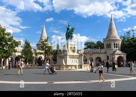 Tourists walk past the equestrian statue of Saint Stephen by Fisherman's Bastion in the Buda Castle District in Hungary Stock Photo