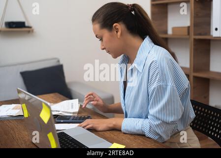 woman accountant, bookkeeping in home. examining annual financial reports, calculating tax rates  Stock Photo
