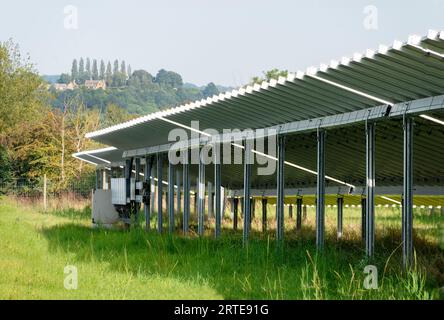 Side,detailed view of solar panels,working units,glowing with and reflecting late afternoon sunlight,showing distant countryside houses on the horizon Stock Photo